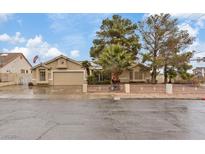 Single story house with a large driveway and mature trees at 390 E Delamar Dr, Henderson, NV 89015