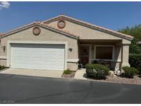Tan stucco house with a two-car garage and nicely landscaped front yard at 4960 Mascaro Dr, Las Vegas, NV 89122