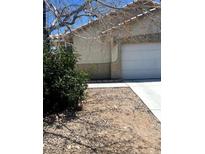 Tan house exterior with white garage door and landscaping at 5607 W Dewey Dr, Las Vegas, NV 89118