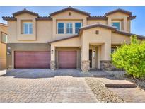 Two-story house with double burgundy garage doors and stone accents at 4165 Kerberos Ave, North Las Vegas, NV 89084