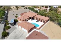 Aerial view of a house with a pool, large yard, and a three-car garage at 6430 Wagon Wheel Ct, Pahrump, NV 89061