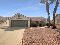 Single-story home with a two-car garage and desert landscaping at 407 Royal Greens Dr, Henderson, NV 89002