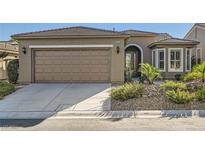 Tan house with a brown garage door and landscaped yard at 10315 Premia Pl, Las Vegas, NV 89135