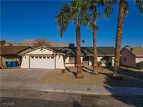 Single story home with a two car garage and mature palm trees at 1294 Amapola Dr, Las Vegas, NV 89142