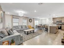 Open-concept living area with gray sectional sofa and kitchen views at 329 Brockbank Pl, Henderson, NV 89011