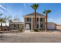 Two story house with a front yard, driveway, and palm trees at 7477 Ullom Dr, Las Vegas, NV 89139