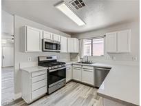 Modern kitchen with white cabinets, stainless steel appliances, and quartz countertops at 1038 Silver Creek Ave, Las Vegas, NV 89183