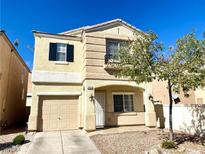 Two-story beige house with a two-car garage and landscaping at 7451 Grizzly Giant St, Las Vegas, NV 89139