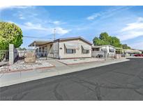 Single-wide manufactured home with carport, landscaped yard, and gated entrance at 5576 Aldama Rd, Las Vegas, NV 89122