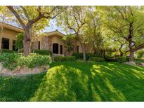 Stone house exterior with lush landscaping and a manicured lawn at 33 Promontory Ridge Dr, Las Vegas, NV 89135