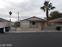 Single story house with gated driveway and palm trees at 1929 Evelyn Ave, Henderson, NV 89011