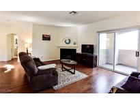 Bright living room with fireplace, hardwood floors, and access to a balcony at 1605 Crimson Hills Dr # 204, Las Vegas, NV 89128