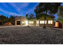 Night view of backyard with gravel and well-lit home at 3647 Waynesvill St, Las Vegas, NV 89122