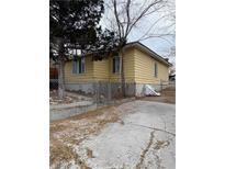 Ranch style home with a yellow exterior, chain link fence, and mature trees at 21 E Ave, McGill, NV 89318
