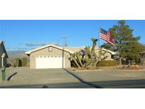 Tan house with a white garage door and American flag at 2231 S Blagg Rd, Pahrump, NV 89048