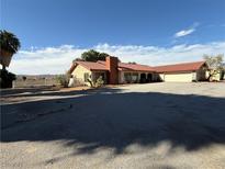 Ranch-style home with red tile roof, large driveway, and desert landscaping at 555 Cooper St, Overton, NV 89040