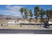 Ranch style home with a white fence, a detached garage, and mature trees at 1720 W Bell Vista Ave, Pahrump, NV 89060
