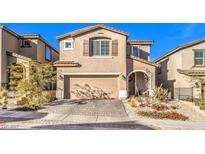 Two-story house with a beige facade, a two-car garage, and a landscaped front yard at 10940 Oregano Ave, Las Vegas, NV 89166