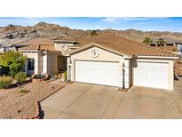 Single-story home with a two-car garage and desert landscaping at 2349 Cottage View Ct, Laughlin, NV 89029