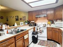 Bright kitchen features wood cabinets, white appliances, and a double sink at 6250 W Flamingo Rd # 135, Las Vegas, NV 89103