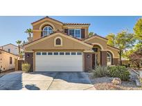 Two-story house with tan exterior, white garage door, and landscaping at 1704 Pinion Mesa Ct, Las Vegas, NV 89128