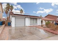 House exterior with a gray garage door, solar panels, and landscaped yard at 6724 Reggie Cir, Las Vegas, NV 89107