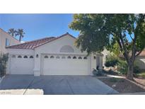 White house with a red tile roof and a two-car garage at 7465 Desert Flame Ct, Las Vegas, NV 89149