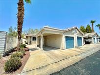 Tan stucco house with blue garage door and covered carport, desert landscaping at 2153 Camel Mesa Dr, Laughlin, NV 89029