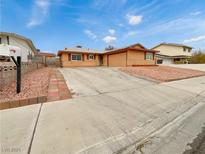 Ranch style home with a large driveway and landscaped front yard at 7704 Macaw Ln, Las Vegas, NV 89145