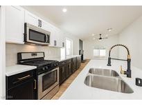 Modern kitchen with black & white cabinets, stainless steel appliances, and quartz countertops at 3718 White Angel Dr, North Las Vegas, NV 89032