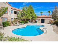 Community pool with lounge chairs and a nearby building at 9580 W Reno Ave # 233, Las Vegas, NV 89148