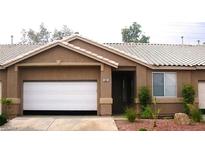 Tan stucco house with tile roof, white garage door, and landscaped yard at 1197 Simms Ave, Henderson, NV 89074