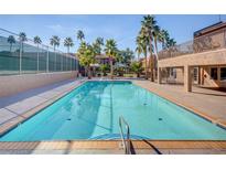 Refreshing community pool with palm trees and surrounding patio area at 5301 River Glen Dr # 210, Las Vegas, NV 89103