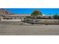 Pink single story home with three car garage, mountain views, and landscaped yard at 6855 Stone Dr, Las Vegas, NV 89110