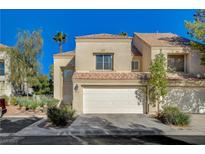 Two-story townhome with white garage door and landscaping at 7844 Bluewater Dr, Las Vegas, NV 89128