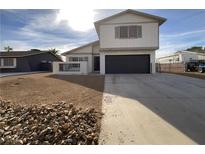 Two-story house with a dark gray garage door and a rock landscaping at 5763 Queenstown Way, Las Vegas, NV 89110
