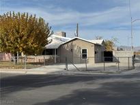 Tan house with a white roof, chain link fence, and mature tree in front at 820 Judson Ave, North Las Vegas, NV 89030