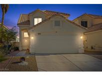 Two-story house with beige exterior, a two-car garage, and landscaping at 1428 Bellglen Dr, Las Vegas, NV 89128