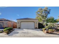 Tan house with a white garage door and nicely landscaped front yard at 5721 Keystone Crest St, North Las Vegas, NV 89081