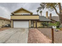 Tan two-story house with attached garage and brick walkway at 4839 W Montara Cir, Las Vegas, NV 89121