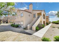 Tan two-story building with stairs and walkway, surrounded by desert landscaping at 3450 Erva St # 207, Las Vegas, NV 89117