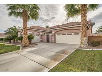 Single-story house with a three-car garage, landscaped yard, and palm trees at 9833 Masterful Dr, Las Vegas, NV 89148