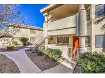 Exterior view of a two-story home with a red door and a walkway leading to the entrance at 1009 Sulphur Springs Ln # 102, Las Vegas, NV 89128