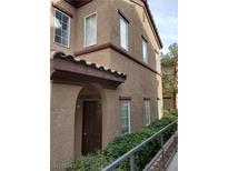 Exterior view of a two-story home with a brown door and landscaped bushes at 7660 W Eldorado Ln # 131, Las Vegas, NV 89113