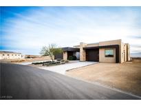 Modern home exterior with wood and stone accents, desert landscaping, and a paved driveway at 6059 E Spring Mountain Blvd, Pahrump, NV 89048