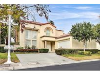 Beige two-story home with a tiled roof, attached garage, and landscaped front yard at 8390 Carmel Ridge Ct, Las Vegas, NV 89113