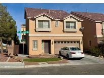 Two-story tan house with attached garage and landscaped front yard at 5186 Bootlegger Ave, Las Vegas, NV 89141