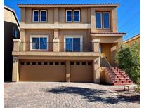 Two-story house with tan exterior, two-car garage, and red brick steps at 9886 Gold Coin Ct, Las Vegas, NV 89141