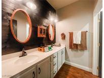 Elegant bathroom with double sinks, wood-look walls, and oval mirrors at 9700 Sandy Turtle Ave, Las Vegas, NV 89149