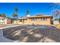 Tan single story house with a rock front yard, driveway and mature palm trees at 2016 Embrey Ave, Las Vegas, NV 89106